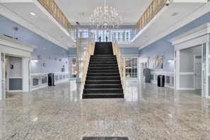 Eine geräumige Lobby mit einer imposanten Treppe, Marmorböden und einem Chandelier.