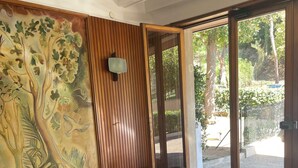 Una habitación con pared de paneles de madera, un vidrio que da al exterior y piso de mármol.