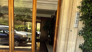 Entrada de hotel con un camino adoquinado, puertas de madera y una planta en maceta.