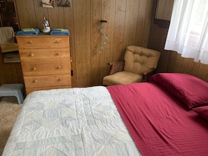 Ein Schlafzimmer mit Bett, Schminktisch, Stuhl und einem kleinen Hocker.