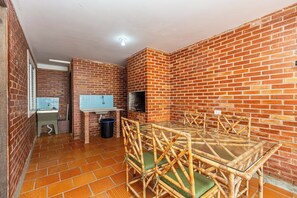 A room with a brick wall, a glass table, and wicker chairs.