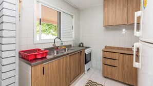 Eine Küche mit Holzausstattung, einer Edelstahlspüle, einem Herd und einem Kühlschrank.