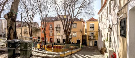 Una calle adoquinada flanqueada por edificios, un árbol y un hidrante rojo.