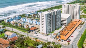 An aerial view of a coastal hotel area with multiple buildings, including high-rise and low-rise structures, near the beach. - Solarium Beach Club - Apartamento T1.307 (Itapoá)