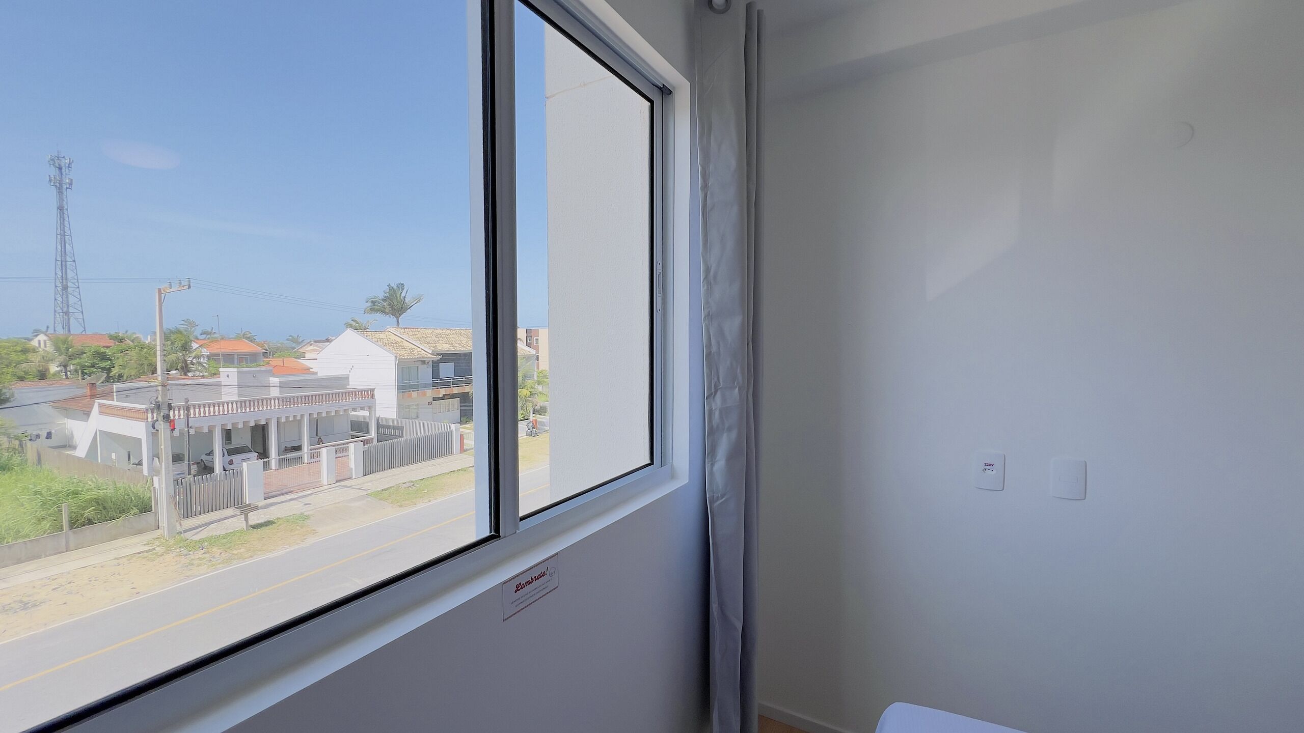 A room with a large window overlooking a street with buildings and a power line tower.