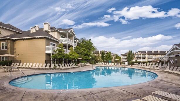 A swimming pool with lounge chairs and a building with balconies.