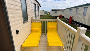 A deck with two yellow lounge chairs and a white railing. - Singh&leite Family L6 (Clacton-on-Sea)