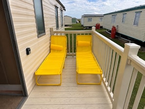 A deck with two yellow lounge chairs and a white railing. - Singh&leite Family L6 (Clacton-on-Sea)
