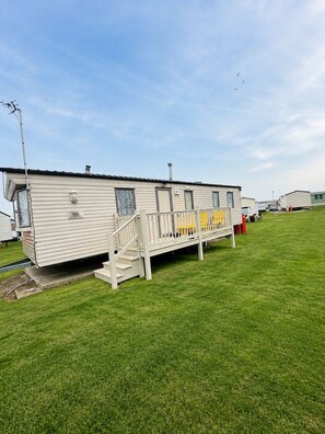 A single-story mobile home with a front porch and a small set of stairs leading to the entrance. - Singh&leite Family L6 (Clacton-on-Sea)