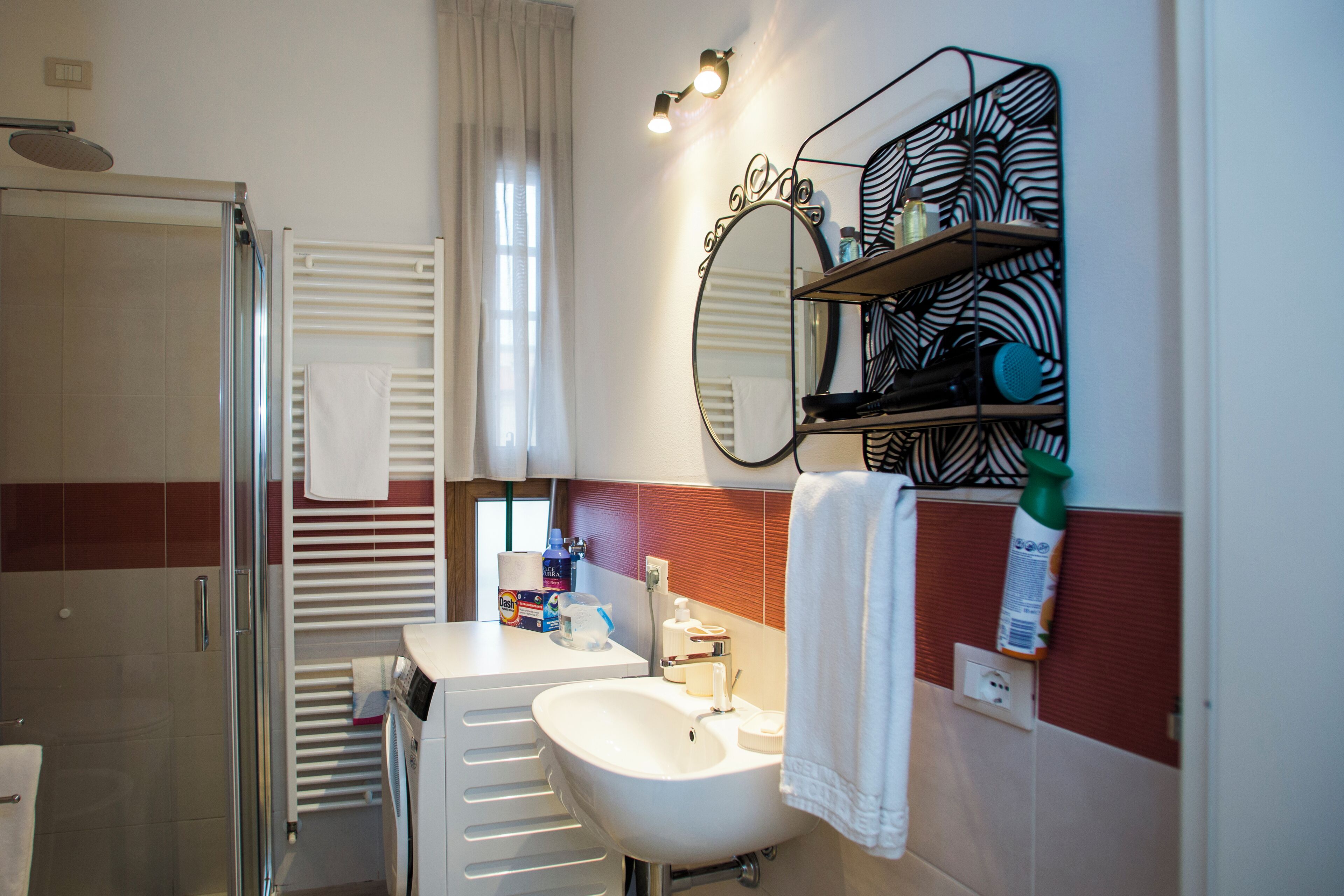 A modern bathroom with a glass shower enclosure, a white sink, and a mirror with a zebra-patterned shelf above it.