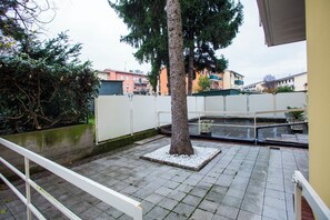 A courtyard with a tree, a small pond, and a white fence.