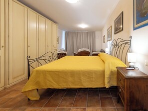 Una camera da letto con un letto, un armadio, un comodino, una lampada e una sedia.