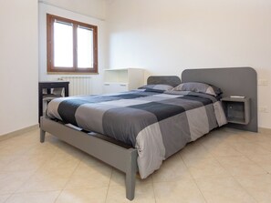 A bedroom with a bed, bedside tables, a window, and a radiator. - Cinquantina by Interhome (Cecina)