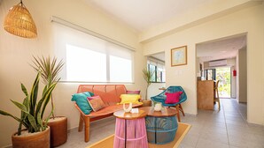 A living room with a sofa, two round tables, and potted plants. - Casa Kolibrí - 8 Bedrooms + Pool + Outdoor Kitchen + Coworking (Mérida)