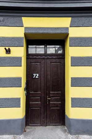 Eine doppelte Holztür mit einem Nummernschild '72' und einem kleinen Fenster darüber.