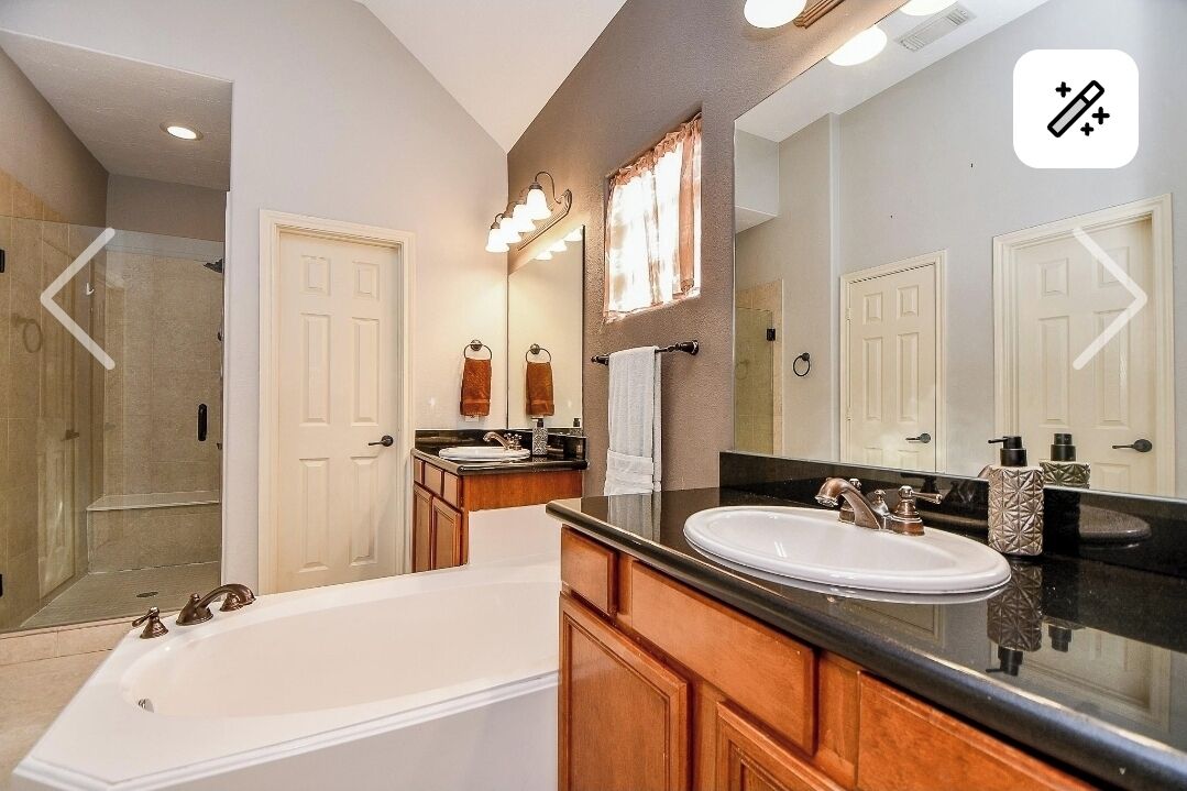 A modern bathroom with a bathtub, a vanity with a sink, and a large mirror.