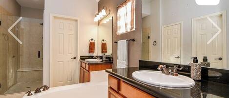 A modern bathroom with a bathtub, a vanity with a sink, and a large mirror.