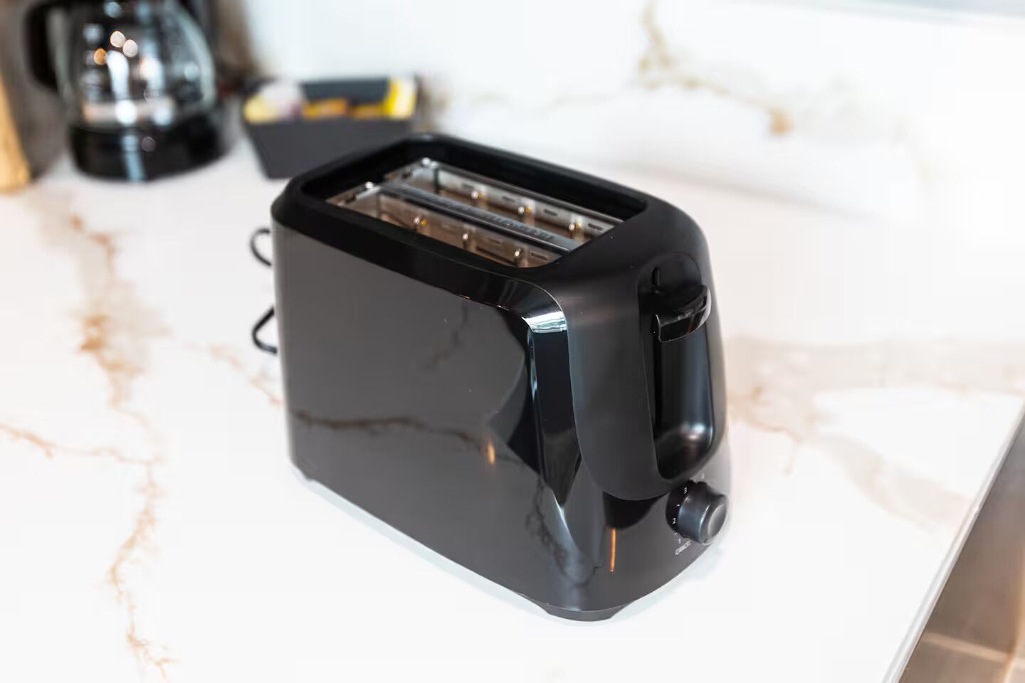 A black toaster on a marble countertop.