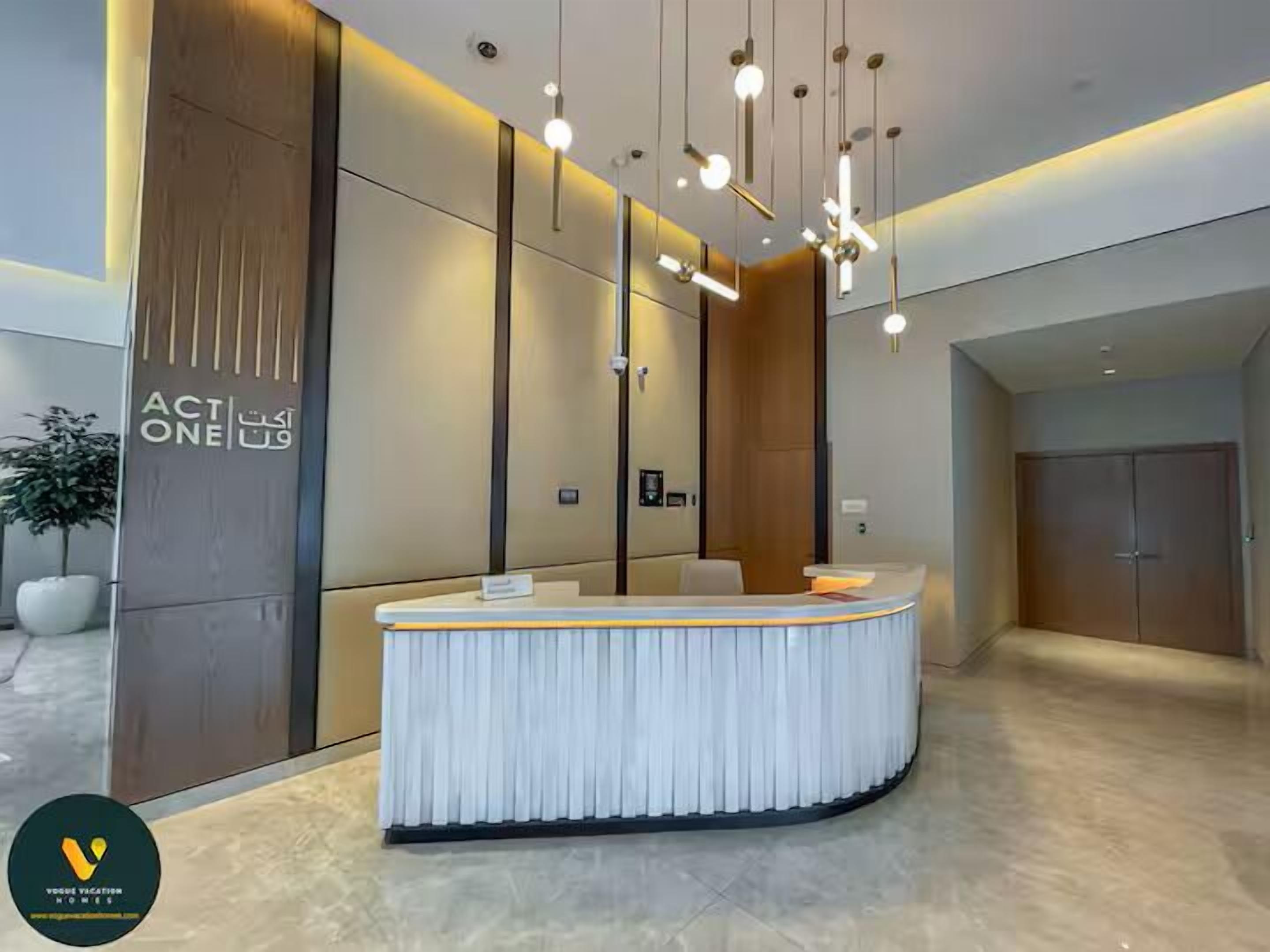 A modern reception area with a curved white reception desk, wooden paneling, and hanging pendant lights.
