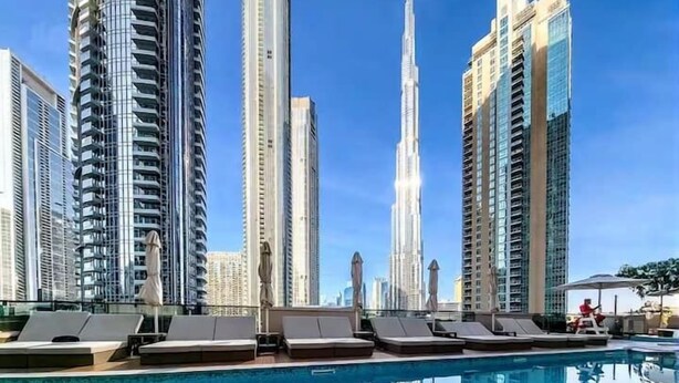 A modern hotel pool area with high-rise buildings in the background, including a prominent skyscraper. - Vogue | Act One near Burj Khalifa | Dubai Mall (Dubai)