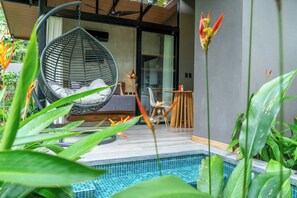 A modern interior with a hanging chair, a small table, and a pool area surrounded by greenery. - Raya Bungalow, AC & Plunge Pool (Punta Uva)