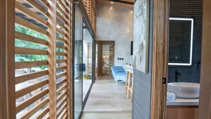 A modern hallway with wooden slats, a blue sofa, and a bathroom with a sink and mirror. - Villa Asencia w/ pool & AC near the beach (Punta Uva)