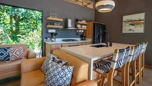 A modern kitchen with a central island, wooden chairs, and a large window overlooking greenery. - Villa Asencia w/ pool & AC near the beach (Punta Uva)