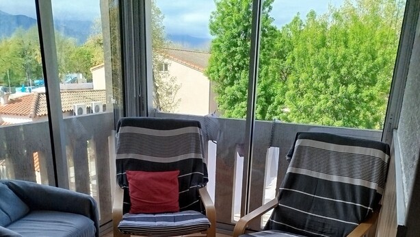A balcony with two wooden chairs, a small round table, and a blue sofa. - Apartment (Argelès-sur-Mer)