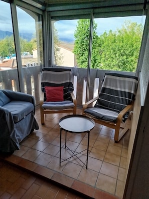 A balcony with two wooden chairs, a small round table, and a blue sofa. - Apartment (Argelès-sur-Mer)