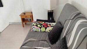 A living room with a sofa, pillows, a small wooden table, and a television mounted on the wall. - Apartment (Argelès-sur-Mer)