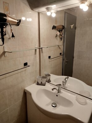 A bathroom with a white sink, a mirror, and a hairdryer on a wall-mounted rack. - Apartment (Argelès-sur-Mer)