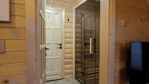 Un intérieur en bois avec une télévision, une porte donnant sur une autre pièce et un luminaire au plafond.