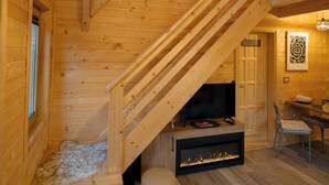 Un intérieur en bois avec un escalier, une cheminée et un luminaire suspendu.