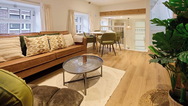 A modern living room with a sofa, a round coffee table, and a dining area with chairs. - Cottage 58B (Twisk)