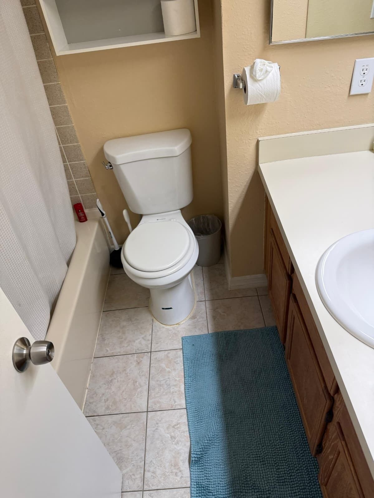 Un baño con inodoro, lavamanos y un tapete azul en el suelo.
