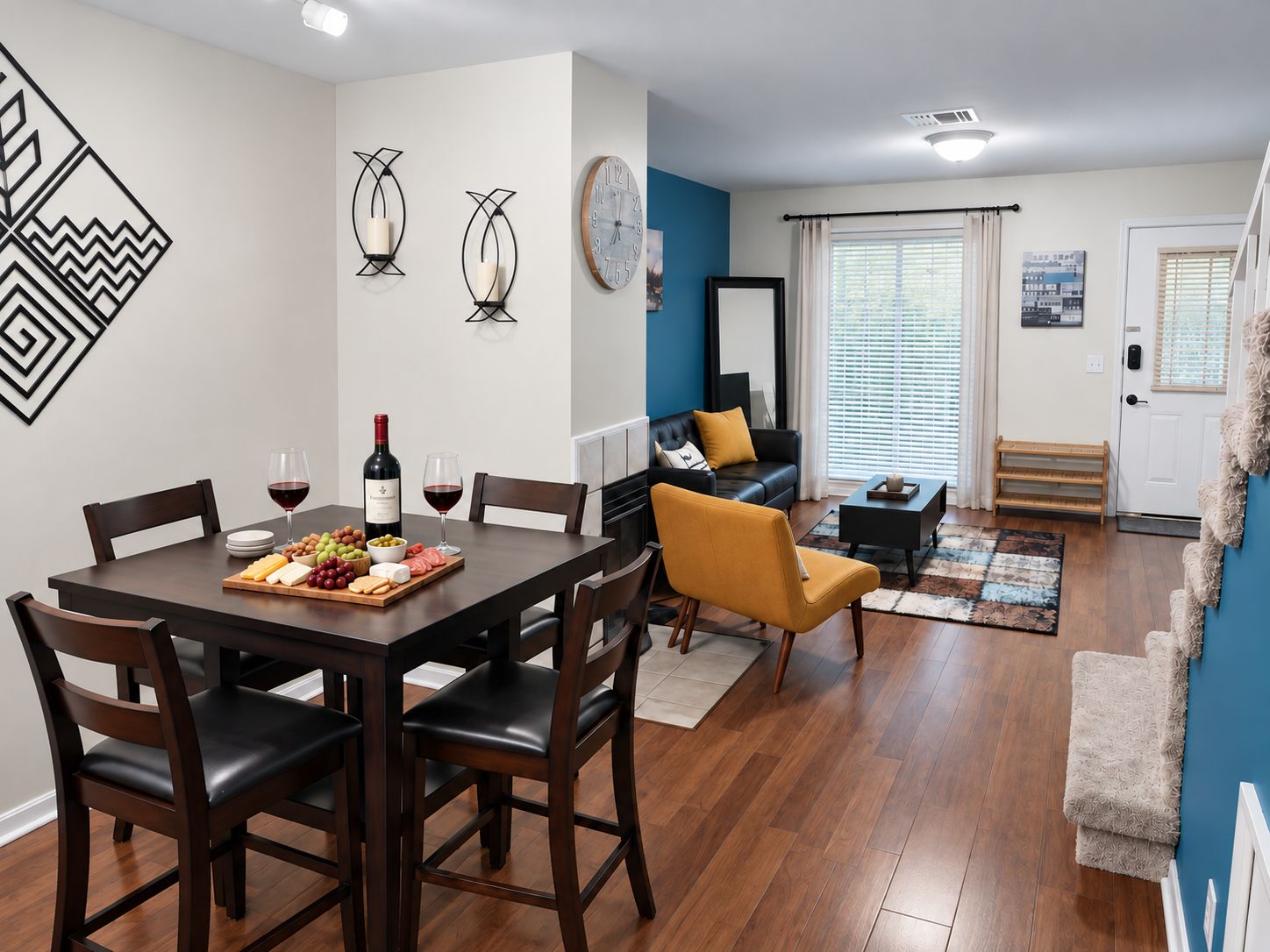 Il y a une salle à manger avec une table en bois, des chaises et une bouteille de vin. On y trouve également un salon avec un canapé, une table basse et un tapis.