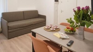 A dining area with a table set for two, a sofa, and a potted plant. - B-Pizzofalcone (Naples)