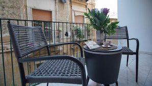 A balcony with two wicker chairs, a small round table with a potted plant, and a magazine. - B-Pizzofalcone (Naples)