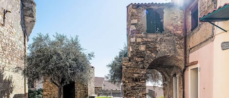 A narrow street with stone buildings, a stone archway, and a sign for 'Casa Loredan'.
