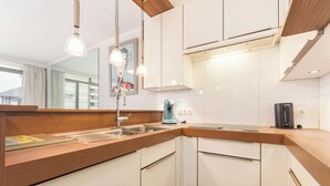 Een moderne keuken met witte kasten, een houten aanrecht, een koffiezetapparaat en hanglampen.