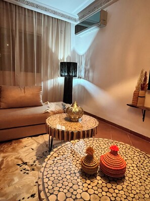 A living room with a sofa, a coffee table with a mosaic top, a lamp, and decorative items. - Superbe appartement au cœur de Marrakech (Marrakech)