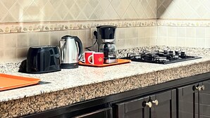Une cuisine avec des meubles de rangement en bois foncé, une cuisinière à gaz, une machine à café et un grille-pain.