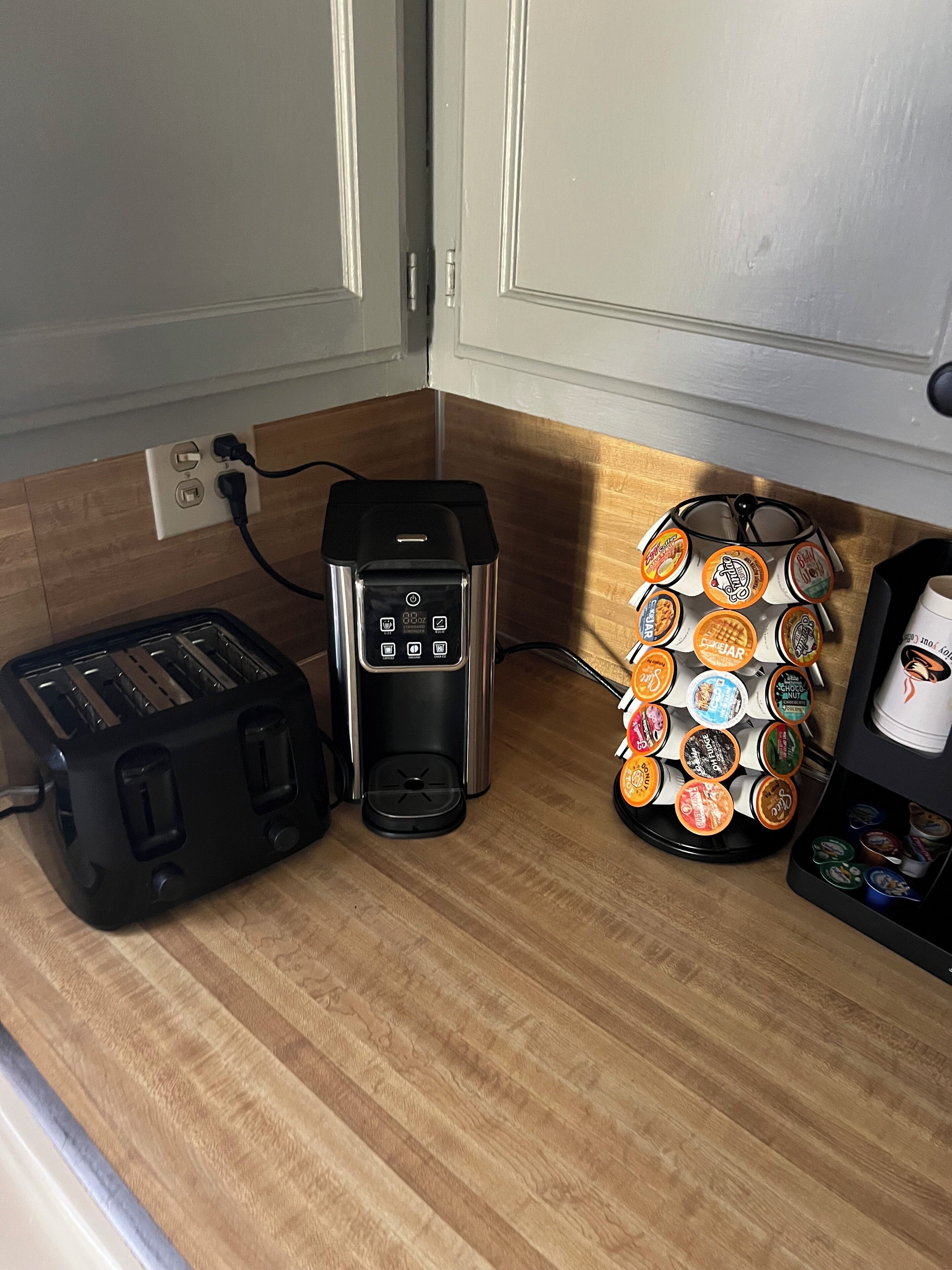 Una encimera de cocina con un tostador, una cafetera y un portal cápsulas de café.