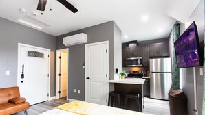 A modern bedroom with a bed, a brown leather chair, and a white bedside table. - Chic Studio – Steps to Dining, Wi-Fi & A/C (San Diego)
