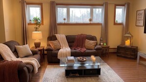 En stue med sofa, to lænestole, et glasbord, en lampe, en gulvlampe, et lille bord med stearinlys, og en vægmonteret globus.