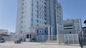A multi-story building with a gated entrance, a covered parking area, and a sign indicating 'SOLARIUM BEACH CLUB.' - Solarium Beach Club - Apartamento T1.505 (Itapoá)