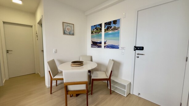 A room with a round table, four chairs, a door, and two wall-mounted pictures. - Solarium Beach Club - Apartamento T1.505 (Itapoá)