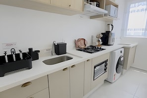 A modern kitchen with a sink, stove, and dishwasher. - Solarium Beach Club - Apartamento T1.505 (Itapoá)