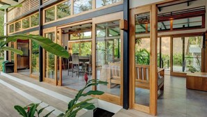 Una casa moderna con amplios ventanales que dan a un patio con mobiliario exterior.