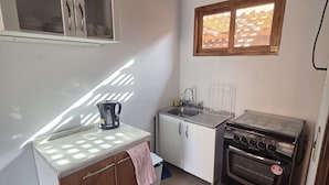 Una cocina compacta con estufa, fregadero y armarios.